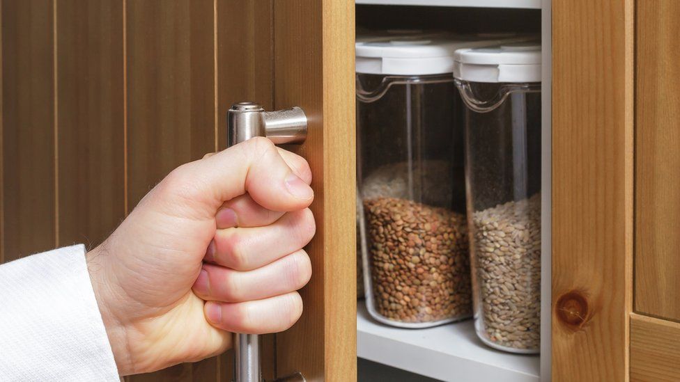 Opening a kitchen cupboard containing storage jars