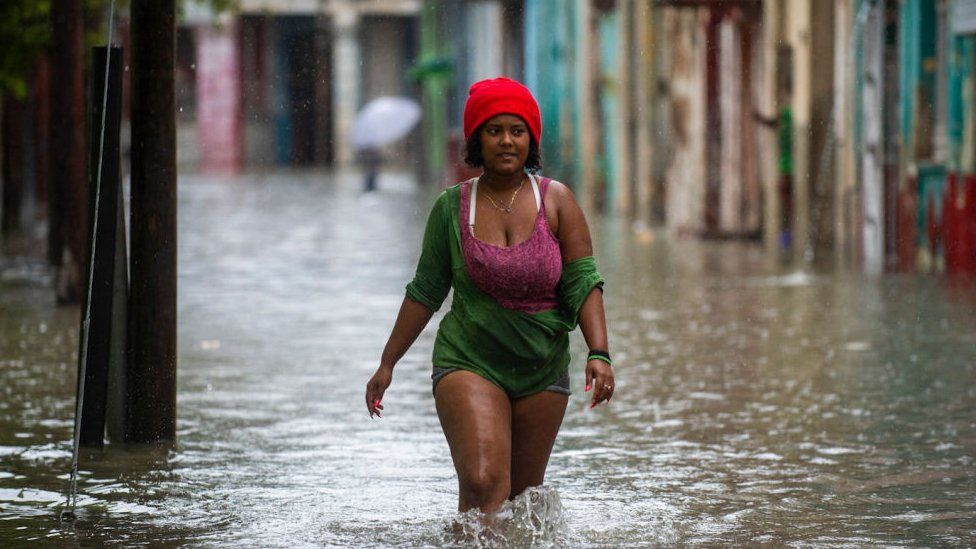 A woman walks through a flooded Havana street