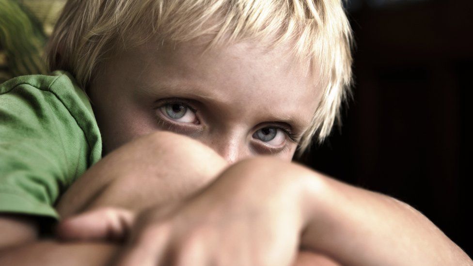 A file photo of a blonde boy with blue eyes cowering