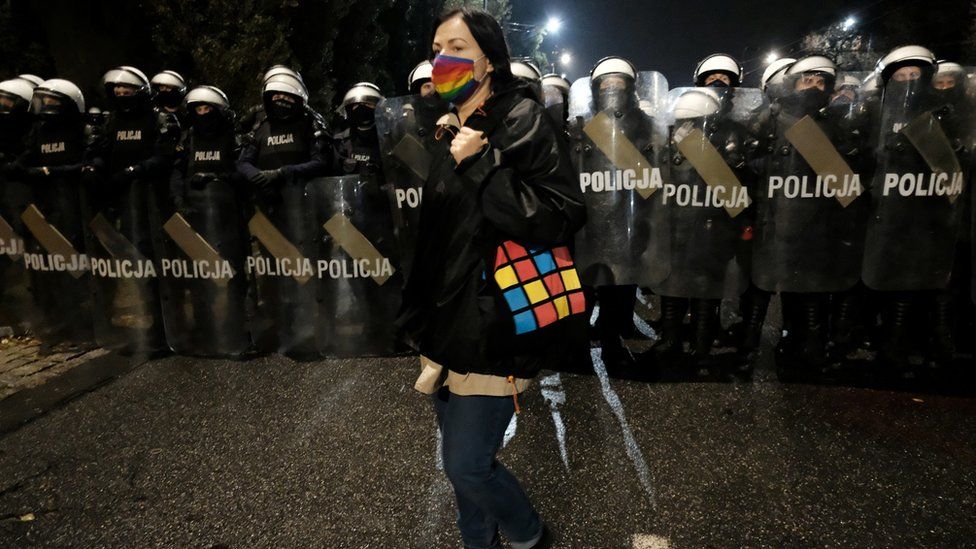 A demonstrator walks in front of police officers blocking a street near the house of Law and Justice leader Jaroslaw Kaczynski during a protest against imposing further restrictions on abortion law, in Warsaw, Poland October 23, 2020.