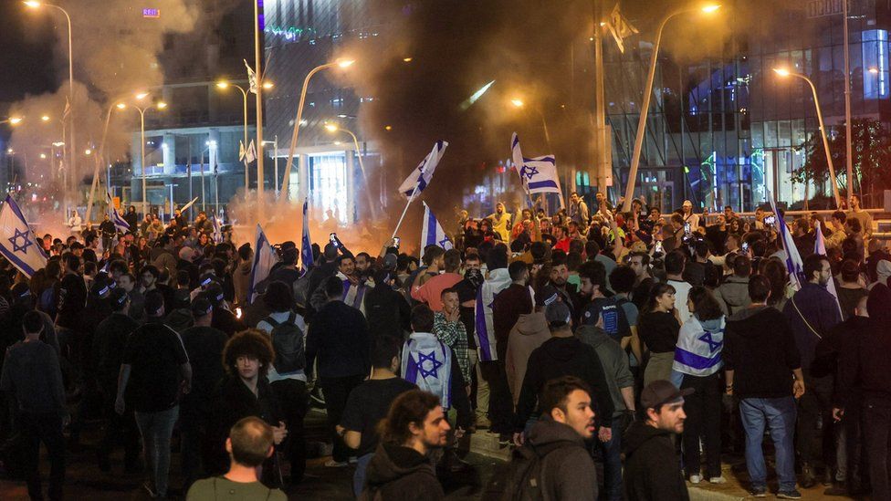 A crowd gathers round a fire during a protest against the Israeli government’s planned judicial overhaul in Tel Aviv, Israel (27 March 2023)
