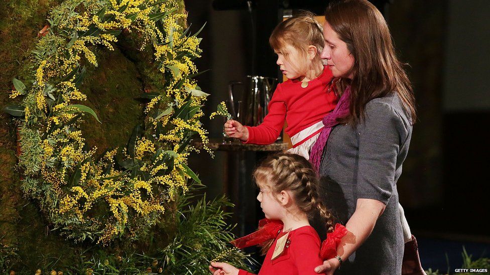 A mother and her two children pin flowers to a wreath in memory of MH17 victims, Canberra, 17 July 2015