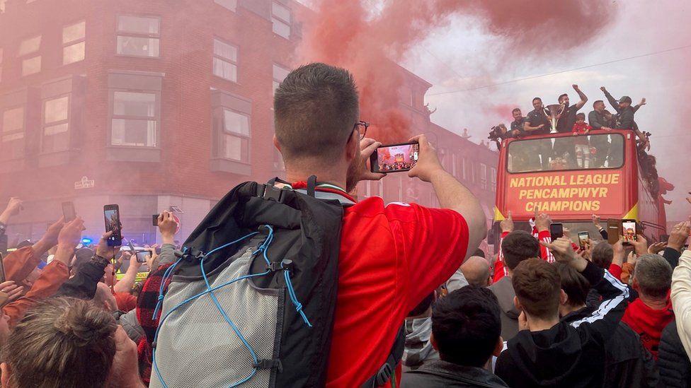 Fans in front of bus with red smoke