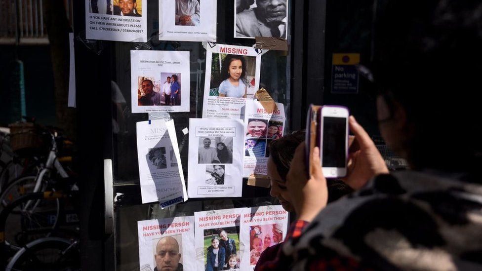 Someone takes a photo of posters of missing people stuck to a telephone box in west London in 2017