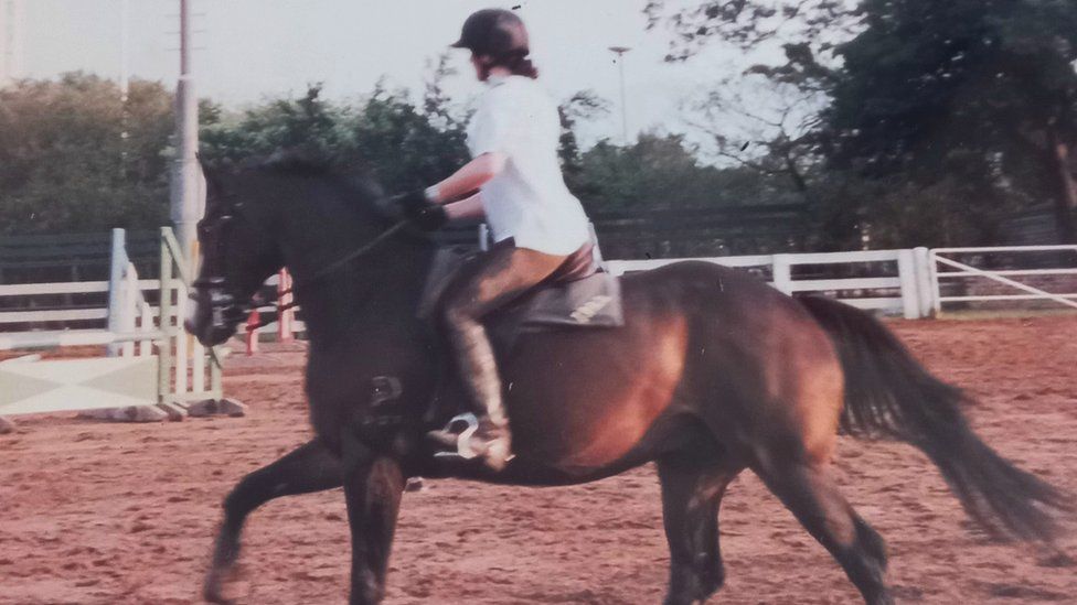 Tess riding a horse in Hong Kong