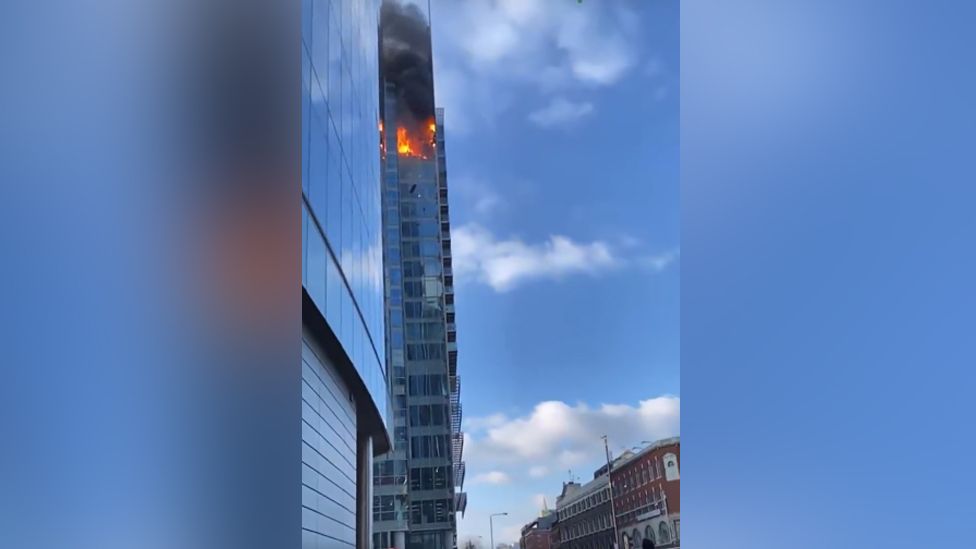 The fire in the tower block with burning debris falling to the ground below