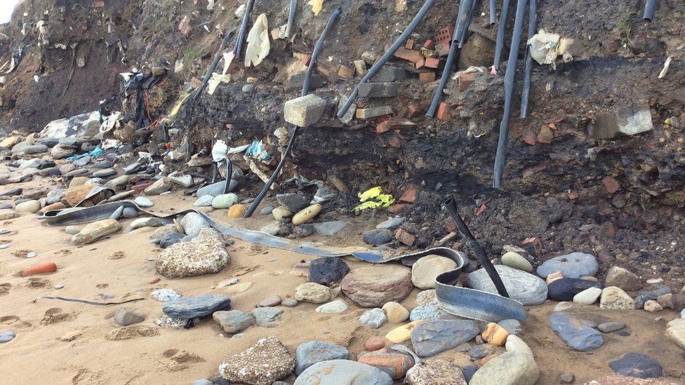 Pipes, cables and other items of rubbish poking through the eroded cliff