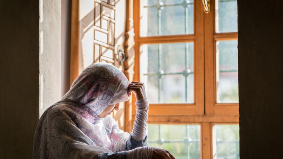 Person in a hijab looking out a window