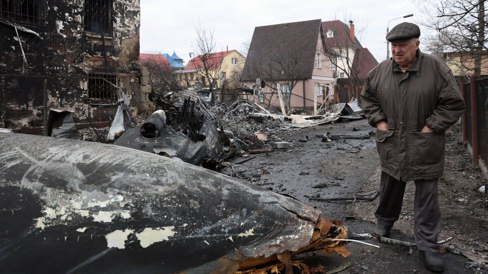A person walks around the wreckage of an unidentified aircraft that crashed into a house in a residential area,