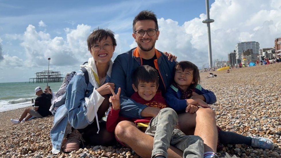 Family photo of Ms Lam-Vechi, her husband and two children at the beach.