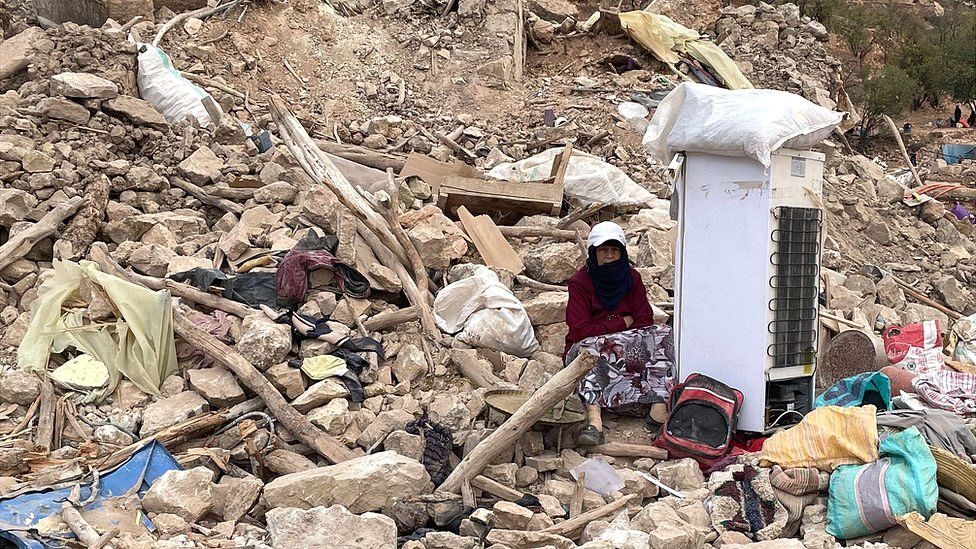 A woman sits among rubble after a powerful earthquake struck the Moroccan village of Douzrou