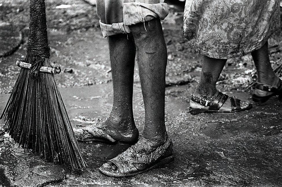A close up of the legs of sanitation workers with a broom