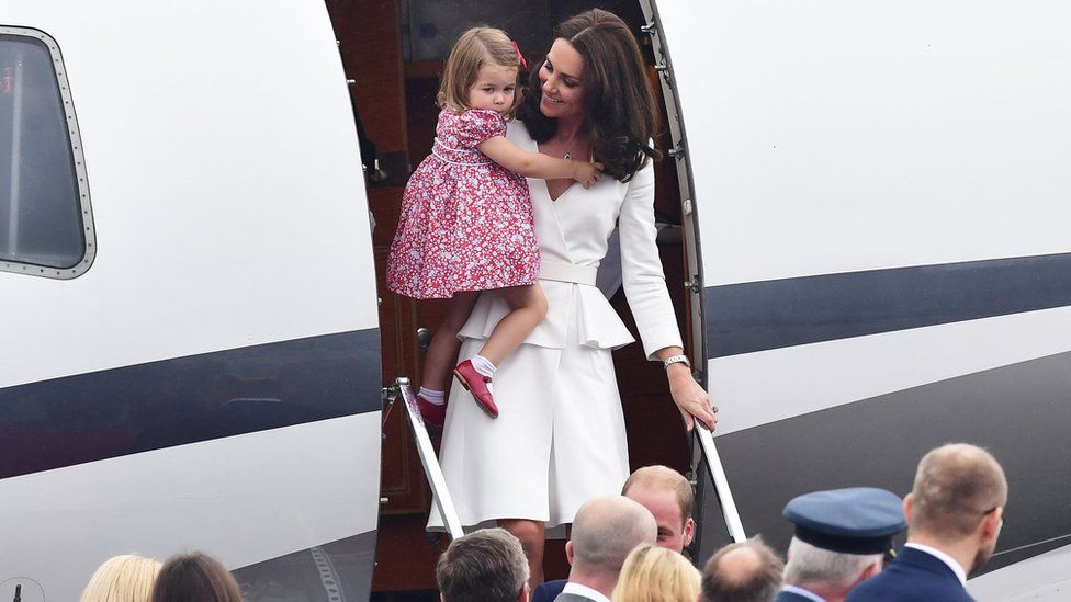 The Duchess of Cambridge carries Princess Charlotte off the plane at Warsaw