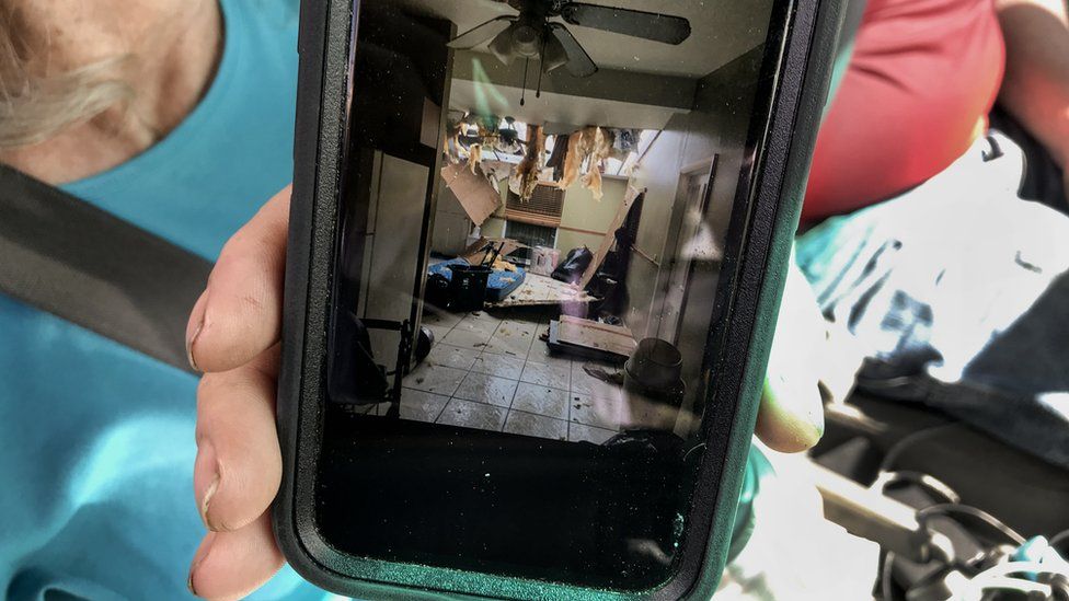 Фотография разрушенного дома Тома и Кэти на мобильном телефоне