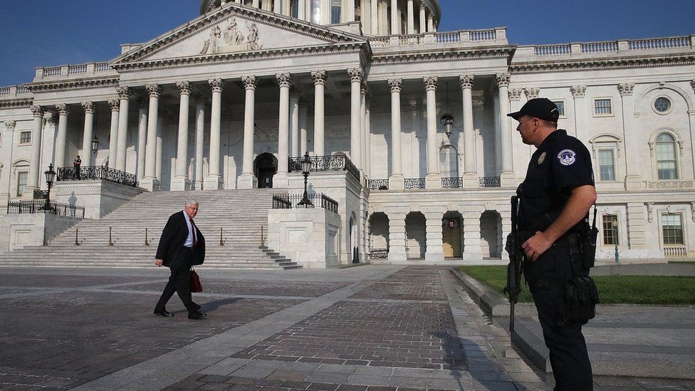 Sen Michael Enzi (R-WY) walks past a US Capitol Police officer standing guard in front of the US Capitol Building, on June 14, 2017 in Washington, DC.