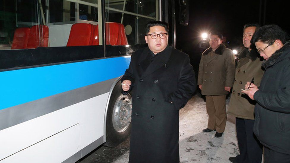 Kim Jong-un smoking a cigarette next to a bus