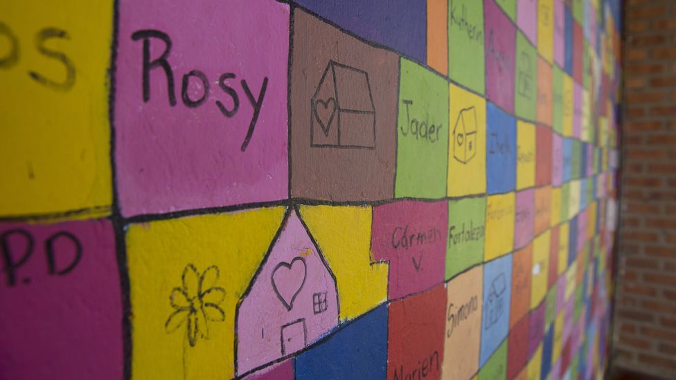 The names of members of the League of Displaced Women and drawings of homes are written on a multi-coloured wall in the City's community centre.