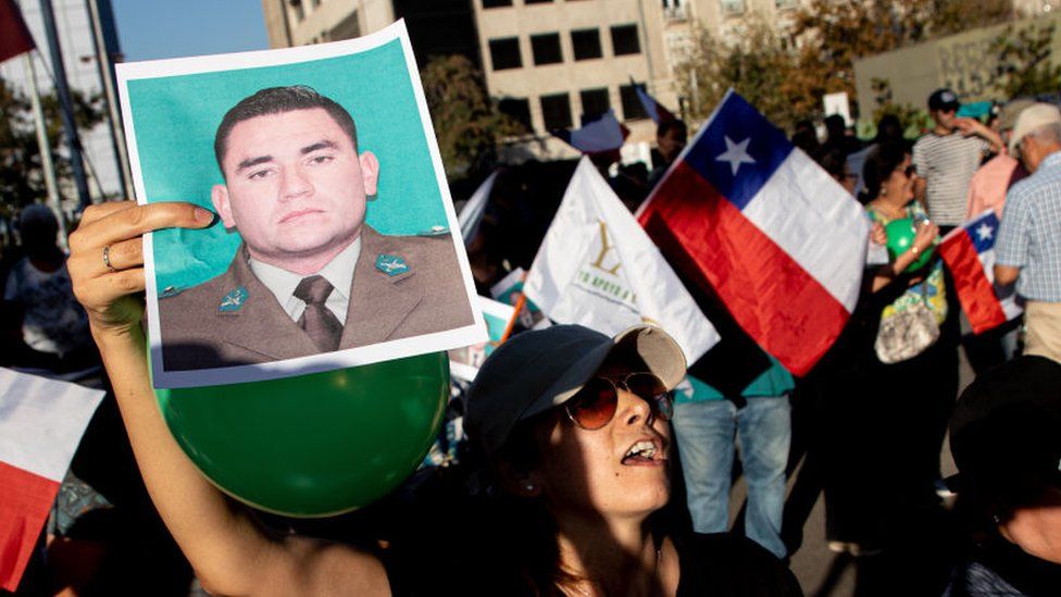 Женщина держит фотографию с лицом Даниэля Пальмы, офицера полиции, который был убит неизвестными рано утром в этот четверг, 6 апреля, во время проверки в Сантьяго 6 апреля 2023 года