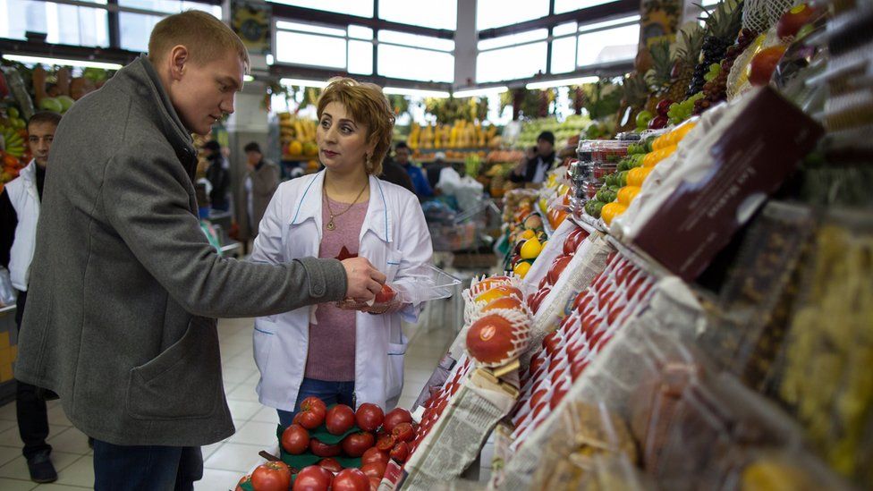 A trader helps a customer to buy tomatoes at Dorogomilovsky food market in Moscow, Russia, Friday, Nov. 27, 2015.