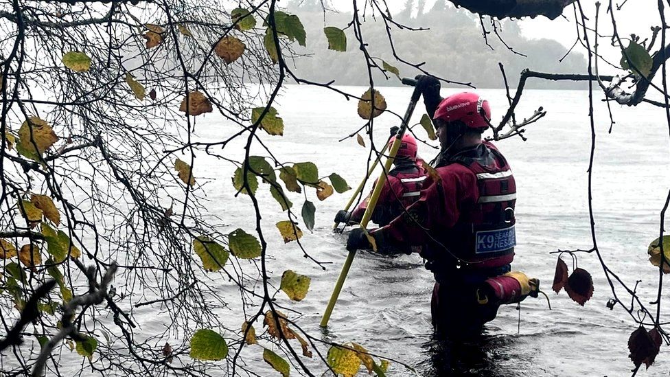Search and rescue workers wade through deep water as they look for a missing person