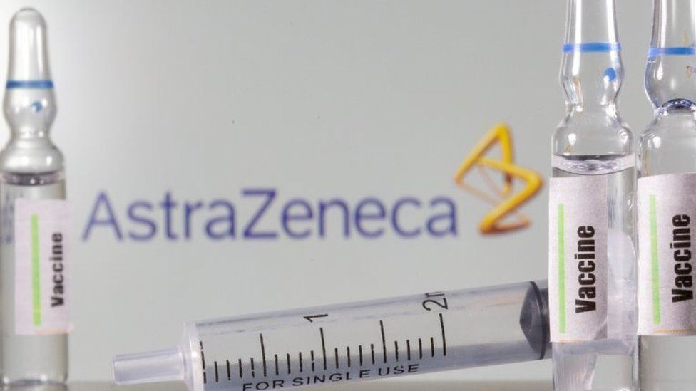A test tube labelled "vaccine" in front of an AstraZeneca logo. File photo