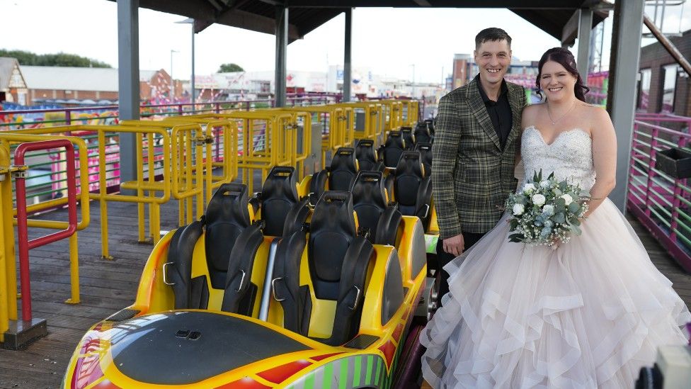 Leanne Smith and Lee Churchill next to a rollercoaster on their wedding day