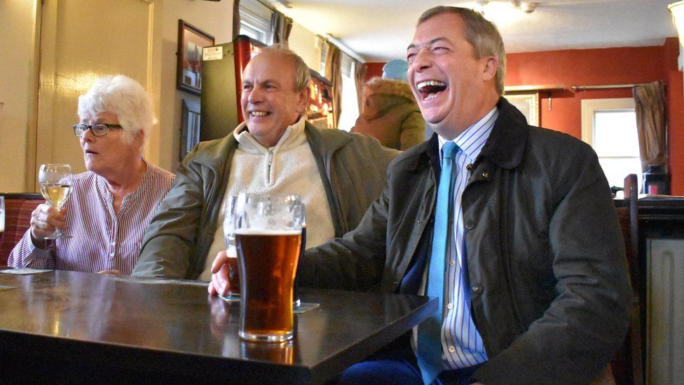 Brexit Party leader Nigel Farage (right) shares a joke with supporters after being bought a pint of bitter by a regular at the Wellington Inn in Eastwood, Nottinghamshire on 15 November