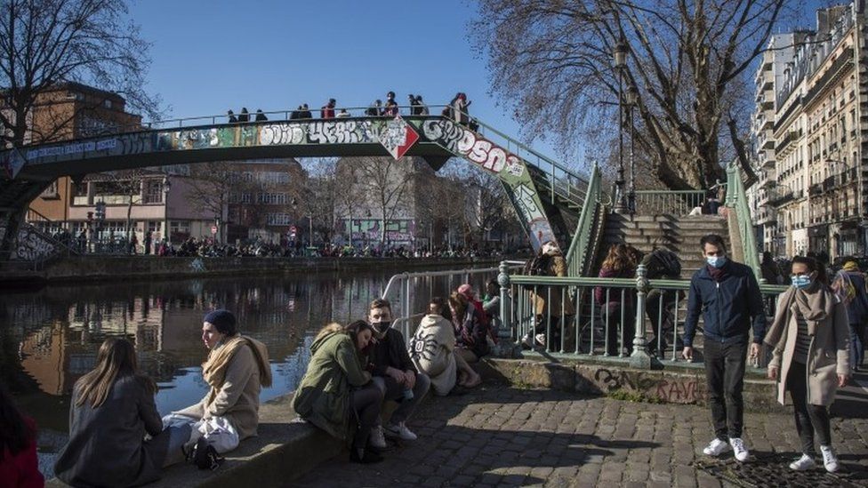 People gather along the banks of the Canal Saint Martin in Paris on Sunday 7 March