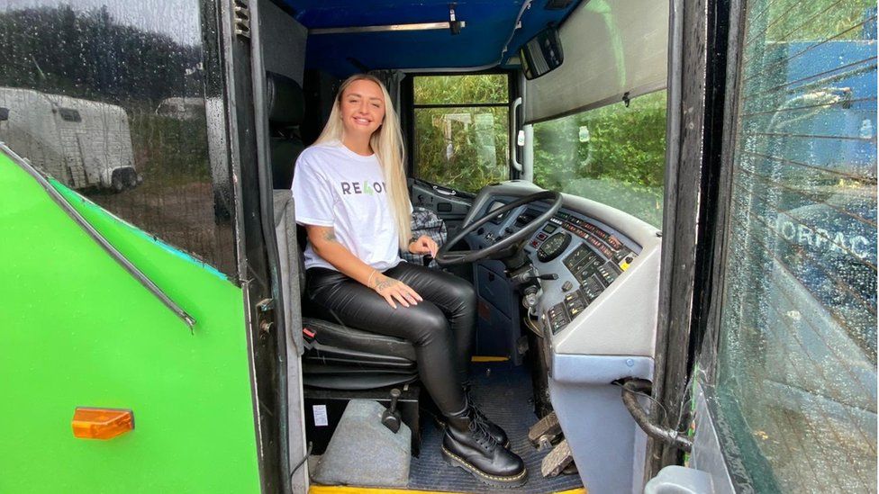 RE4orm volunteer sitting in the driver's seat of the bus