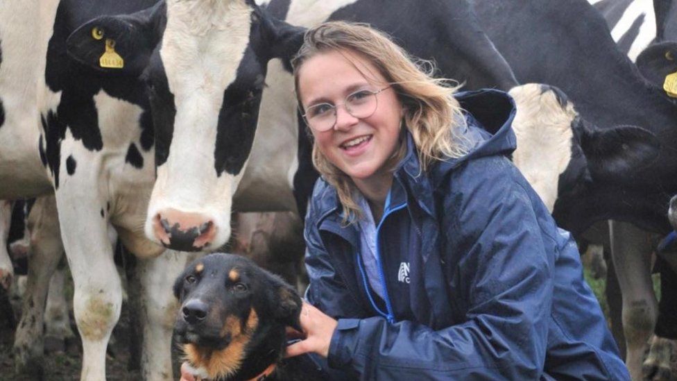 Mary crouching beside a dog with a cows right behind her