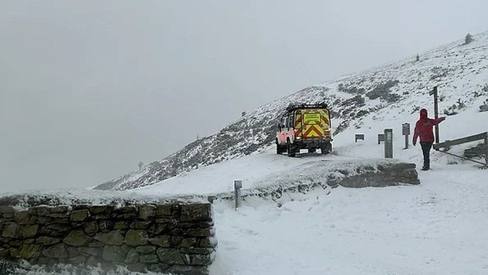 Snowy scene at the foot of Moel Famau with a land rover and person in winter parka