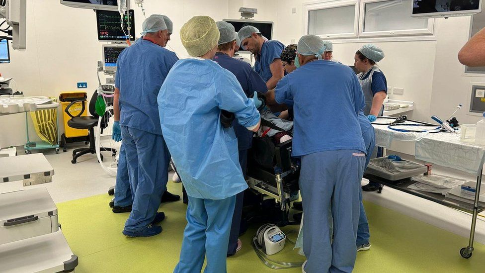 A team of doctors stand around a patient during surgery