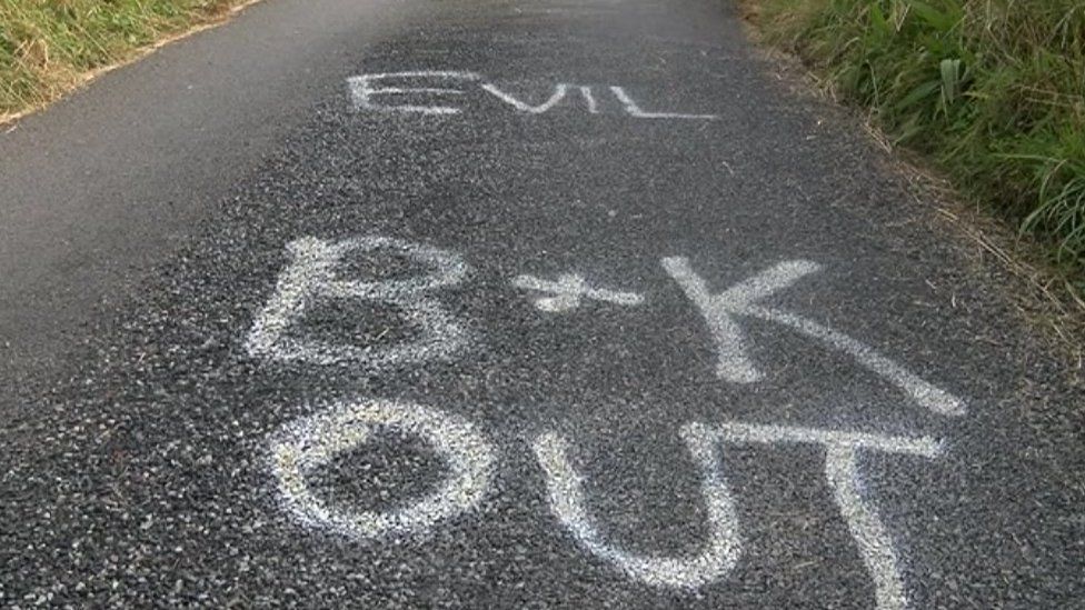 The words "evil B&K out" spray painted on a road