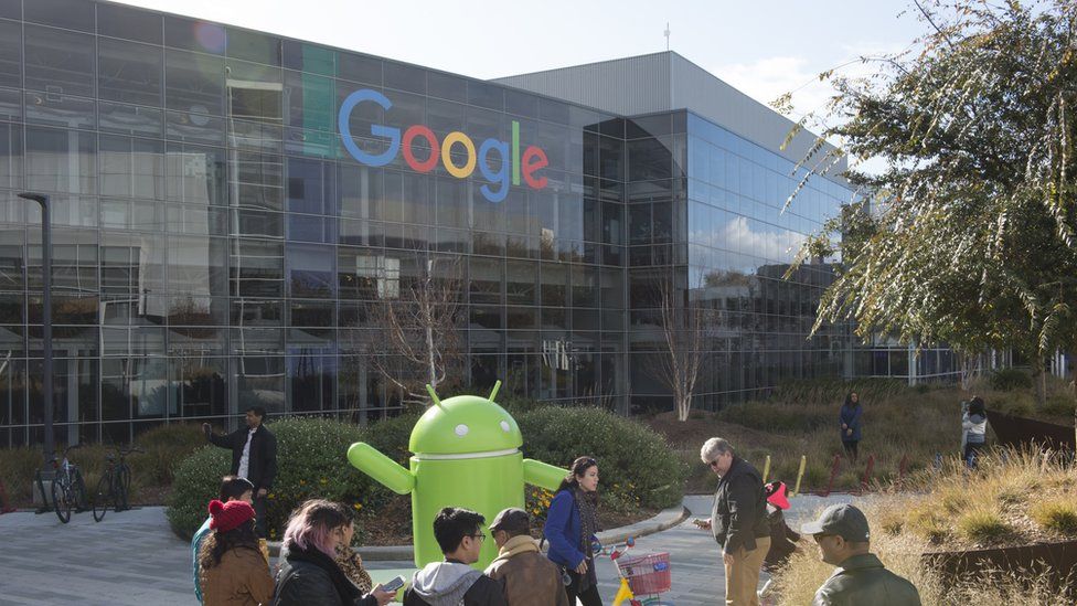Tourists stand in front of a giant Google Android mascot at Google HQ