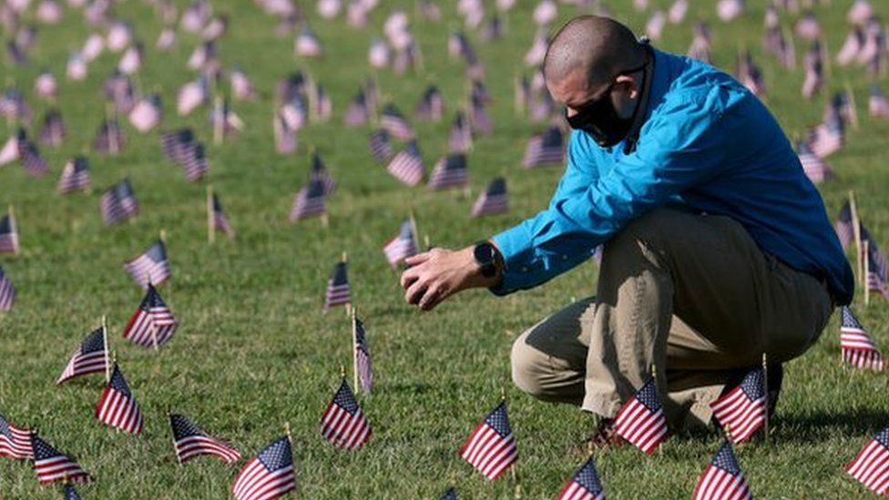 Chris Duncan, whose 75 year old mother Constance died from Covid, seen at September memorial among small US flags to commemorate the Covid dead