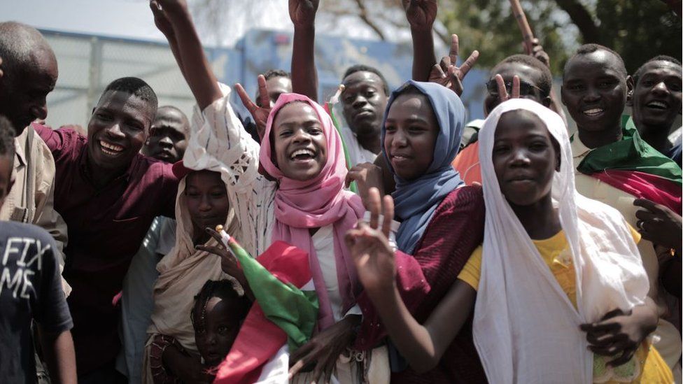 Sudanese men and women celebrate outside the Friendship Hall in the capital Khartoum where generals and protest leaders signed a historic transitional constitution meant to pave the way for civilian rule in Sudan, on August 17, 2019