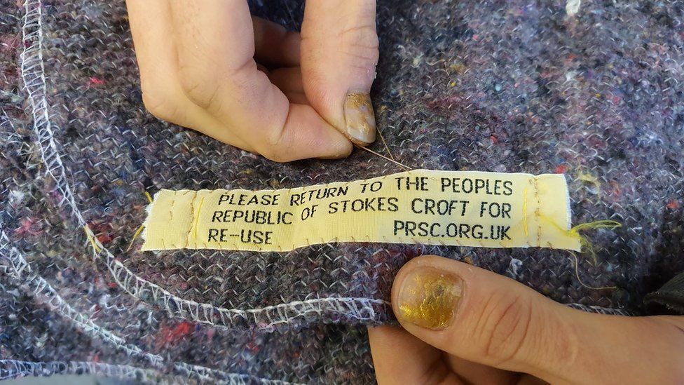 Label being sewn onto a blanket for a homeless person to use