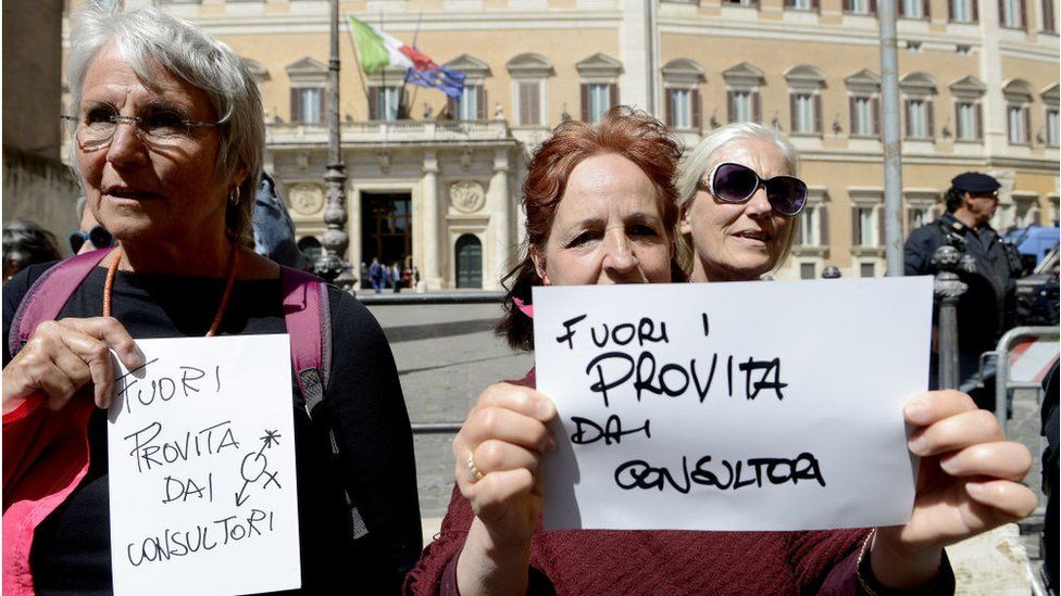 Two women hold signs reading "Pro-life, get out of the clinics" during a protest in Rome