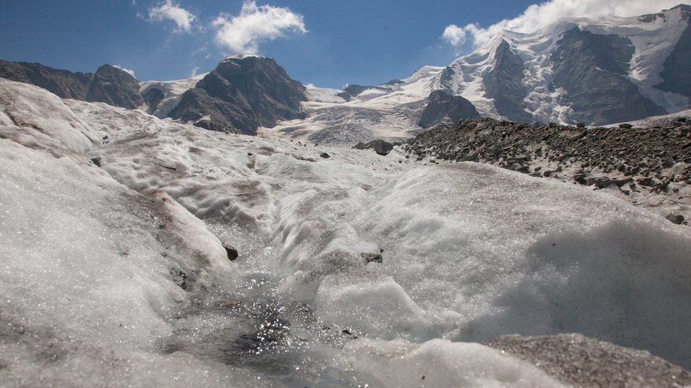 Талая вода течет по льду ледника Перс перед горой Пиц Палуэ недалеко от альпийского курорта Понтрезина, Швейцария
