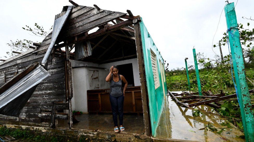 A woman stands among the rubble of a home in western Cuba