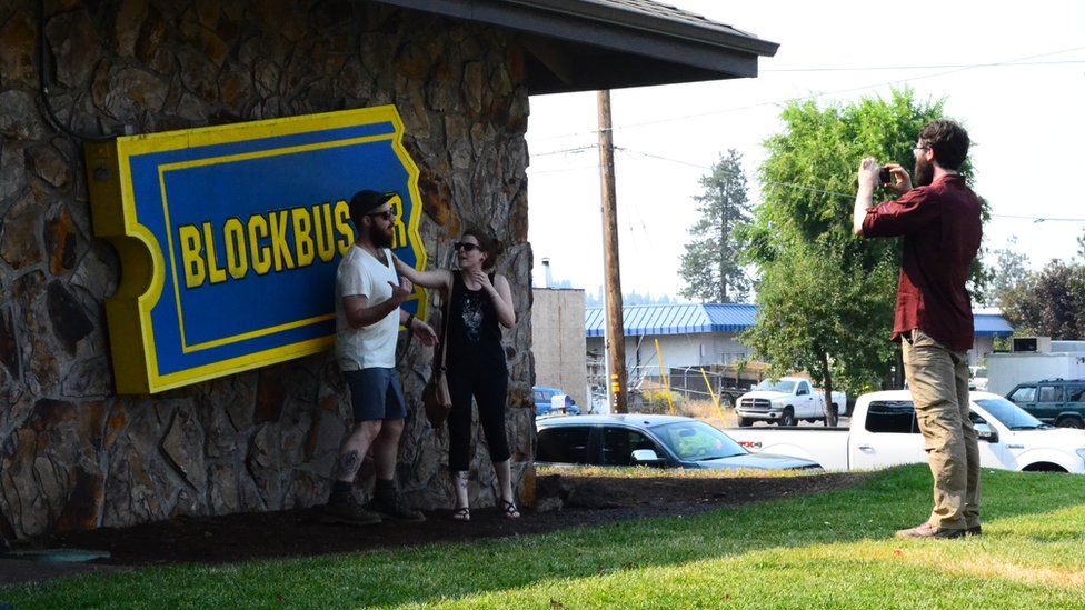 Tourists take pictures in front of Blockbuster sign