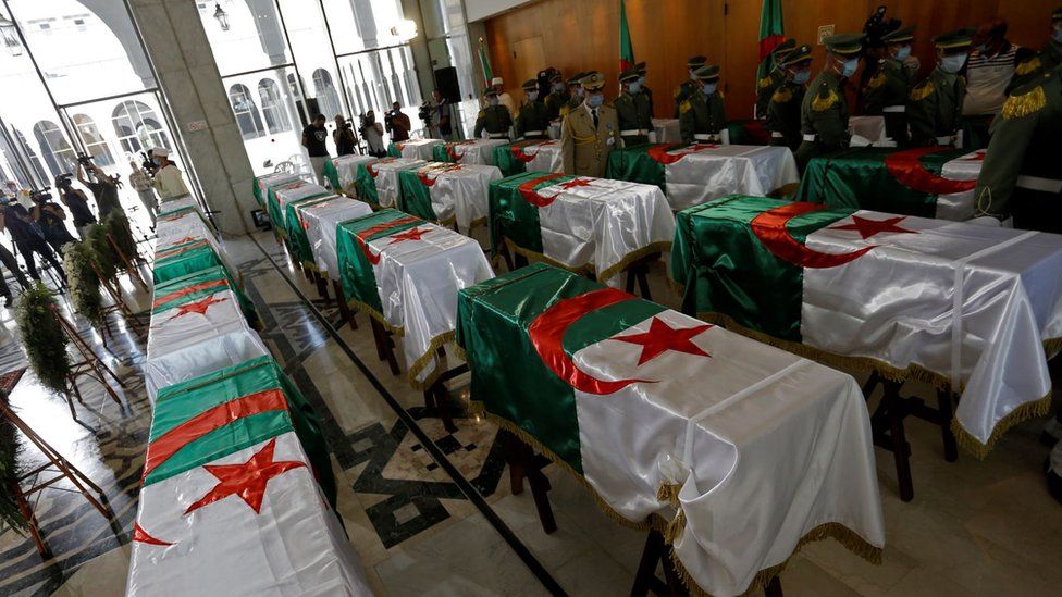 A soldier stands guard next to the national flag-draped coffins containing the remains of 24 Algerian resistance fighters decapitated during the French occupation, at the Moufdi-Zakaria culture palace in Algiers, Algeria, 04 July 2020.