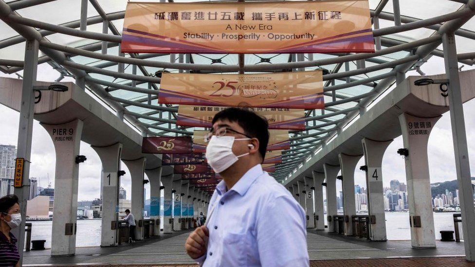 A man walks past banners at a ferry pier with a slogan celebrating the upcoming 25th anniversary of Hong Kong's handover from Britain to China, in Hong Kong on June 16, 2022.