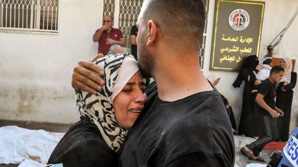 A man comforts a woman mourning outside the morgue of al-Shifa hospital in Gaza City on October 12, 2023