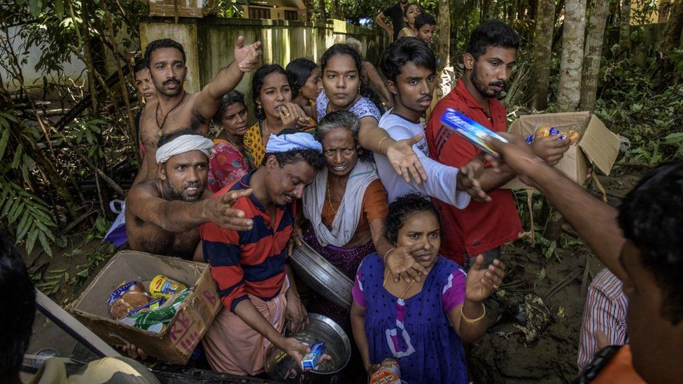 Men and woman receiving food supplies by a riverside