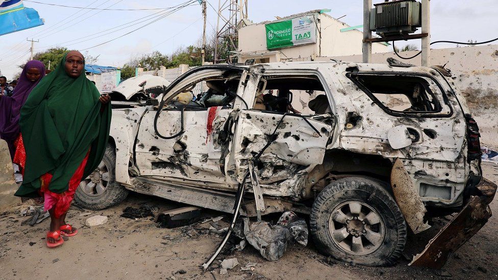 Somali women walk near the wreckage of a car destroyed at the scene of a militant attack at the Elite Hotel in Lido beach, in Mogadishu, Somalia August 17, 2020