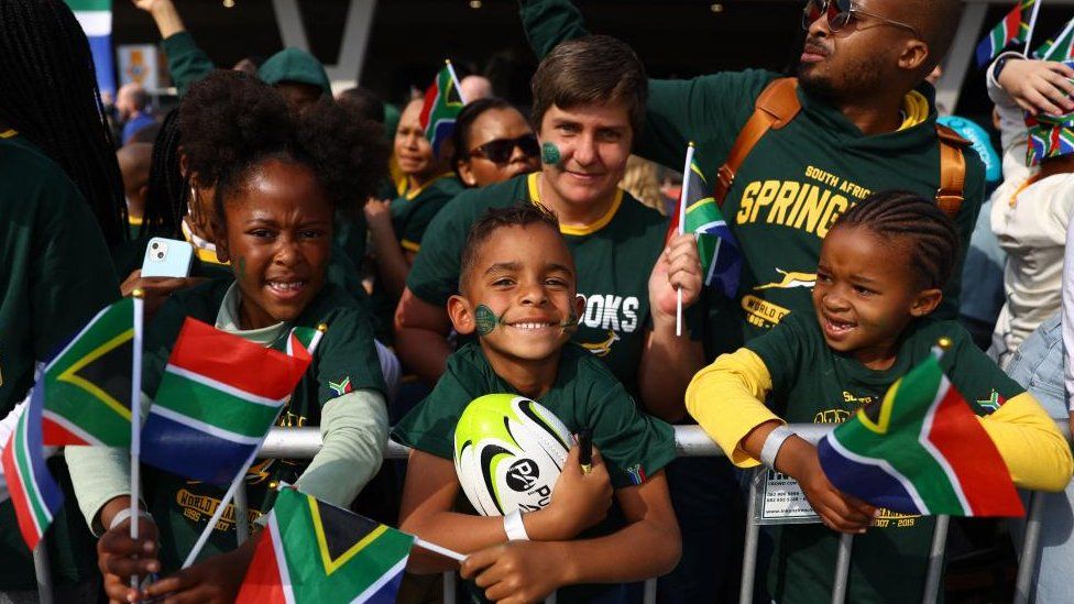Children holding South African flags and rugby balls at OR Tambo International Airport, Johannesburg, South Africa - Saturday 12 August 2023