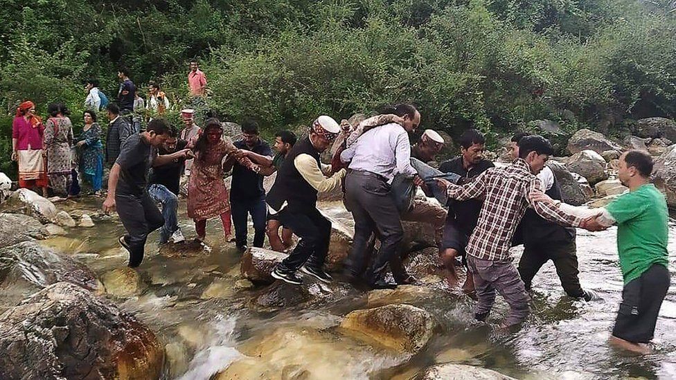 People carrying injured across a creek