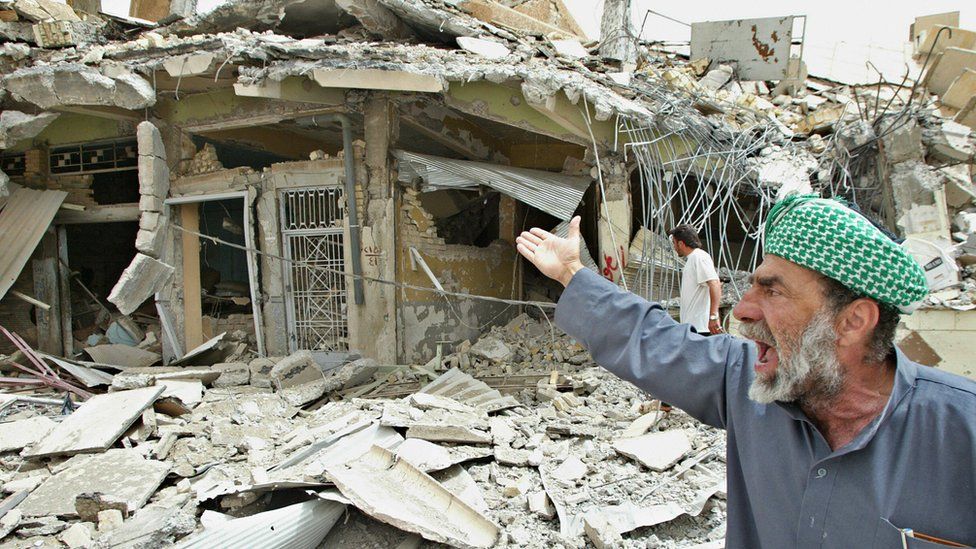 An Iraqi man reacts in front of destroyed houses in the city of Falluja on 30 April 2004
