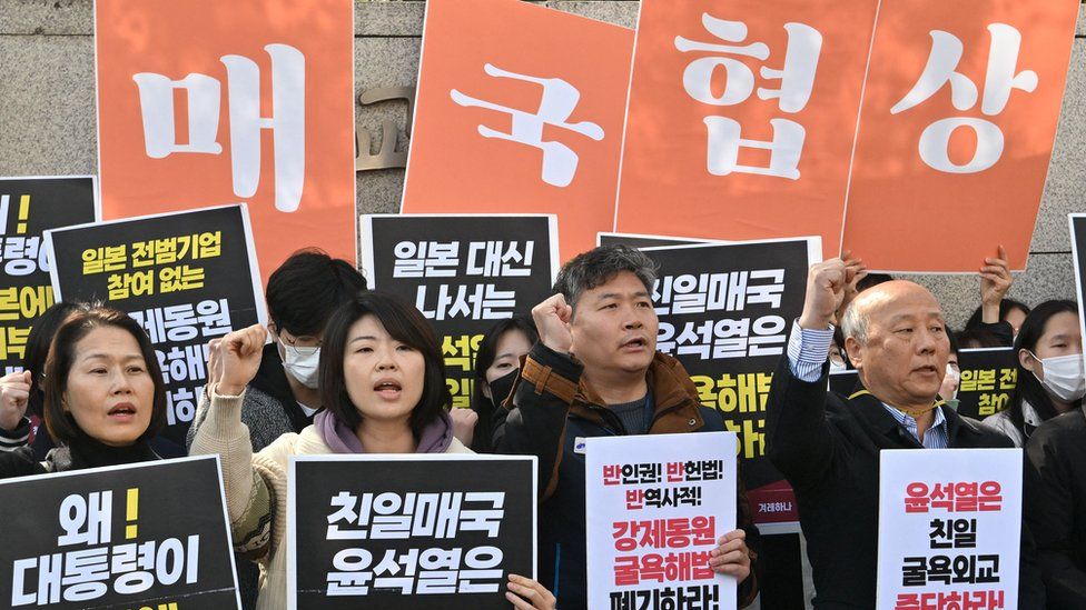 Protesters in Seoul hold up placards saying "Negotiations of betrayal"